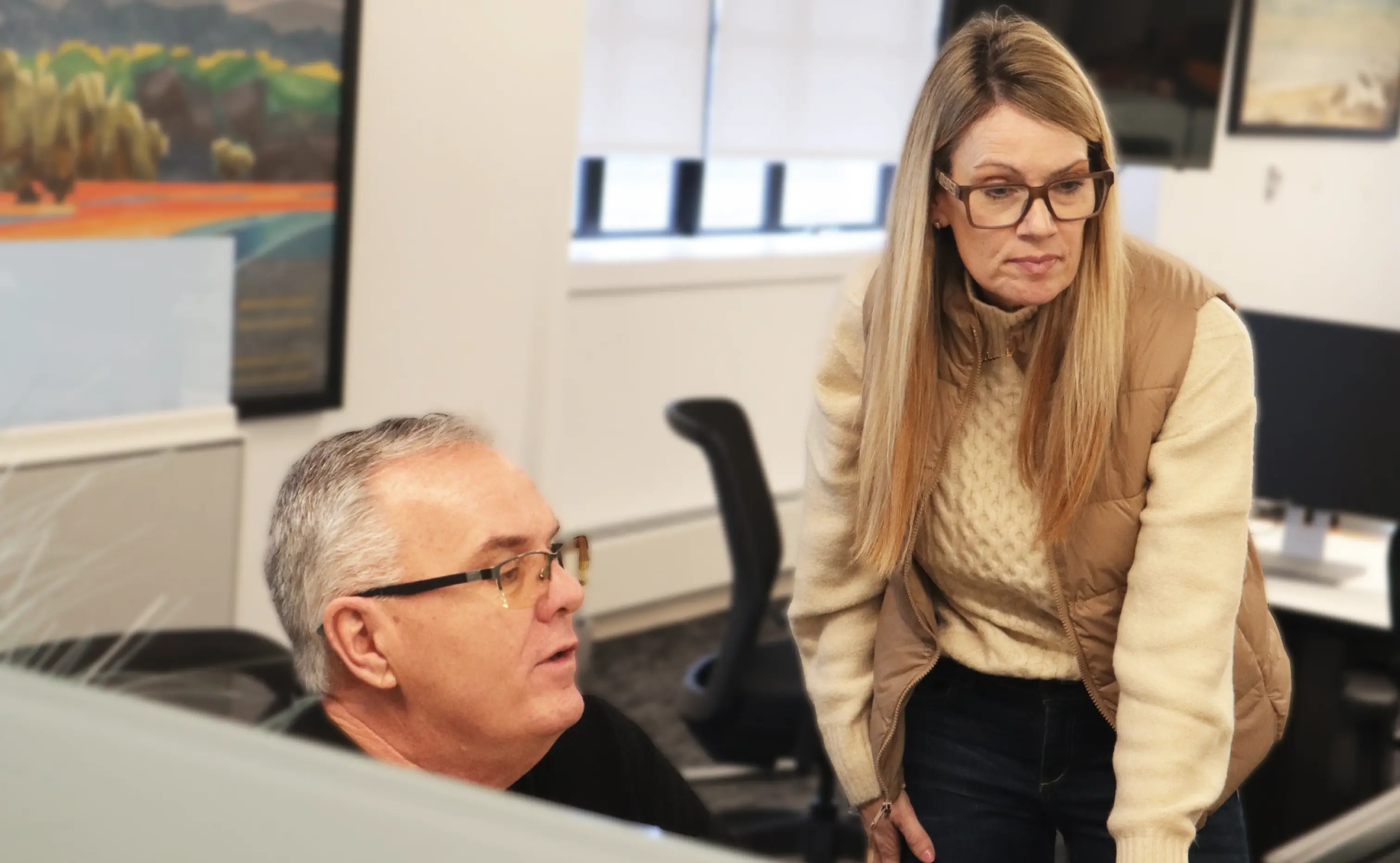Man and women sat at an office desk looking at a screen
